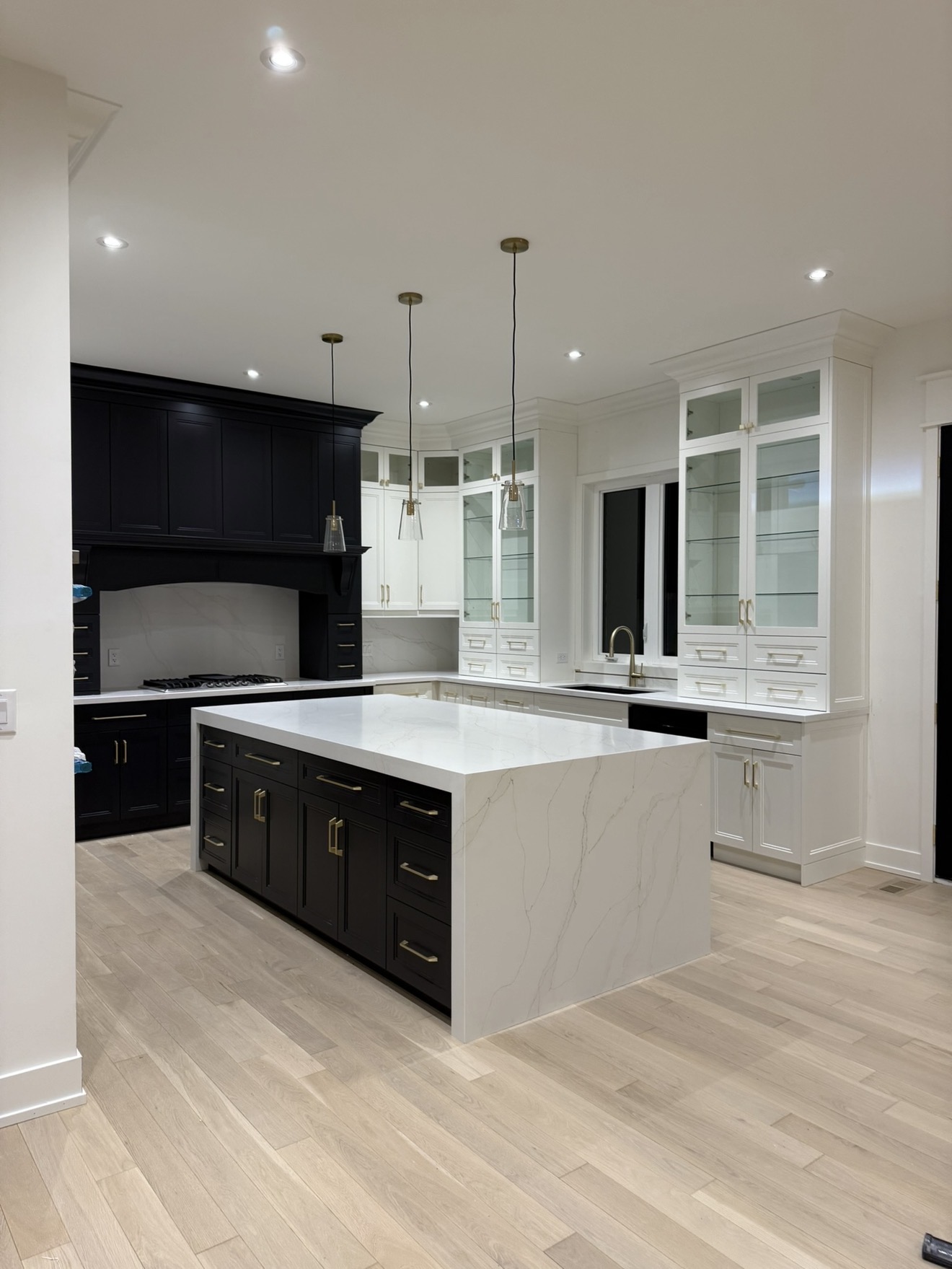 High-contrast kitchen with black lower cabinets and white upper glass-front cabinets
